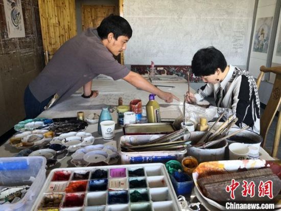 圖為2020年8月下旬，敦煌“80后”畫家張杰龍(左)在為云南麗江“學(xué)生”莫北講解敦煌壁畫的繪畫技巧?！●T志軍 攝