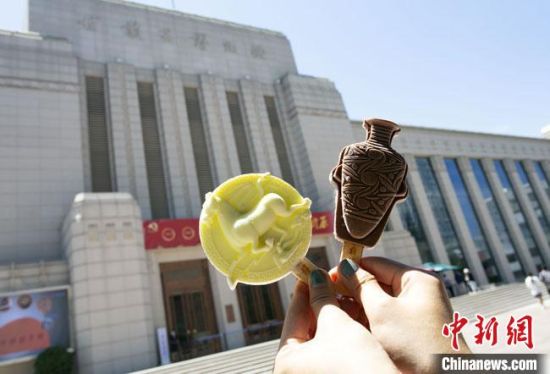 2021年7月30日，游客手拿“銅奔馬”“彩陶瓶”造型的雪糕，在甘肅省博物館前拍照打卡?！「哒?攝