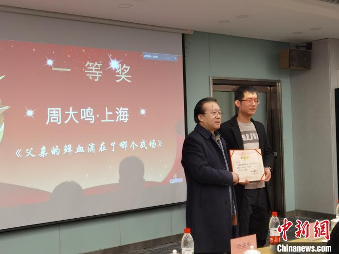 圖為作家、西北師范大學(xué)新聞與傳媒學(xué)院院長(zhǎng)徐兆壽頒發(fā)一等獎(jiǎng)證書(shū)，代領(lǐng)獎(jiǎng)?wù)呱吓_(tái)領(lǐng)獎(jiǎng)?！钅?攝