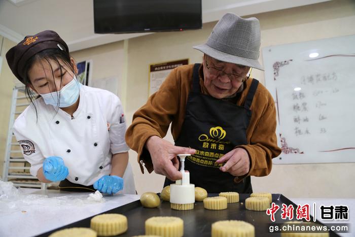 當日，受邀參加活動的臺胞臺屬代表、兩岸婚姻及子女、在甘臺商代表等歡聚一堂。圖為77歲的在甘臺胞潘天鑒制作月餅。九美旦增 攝