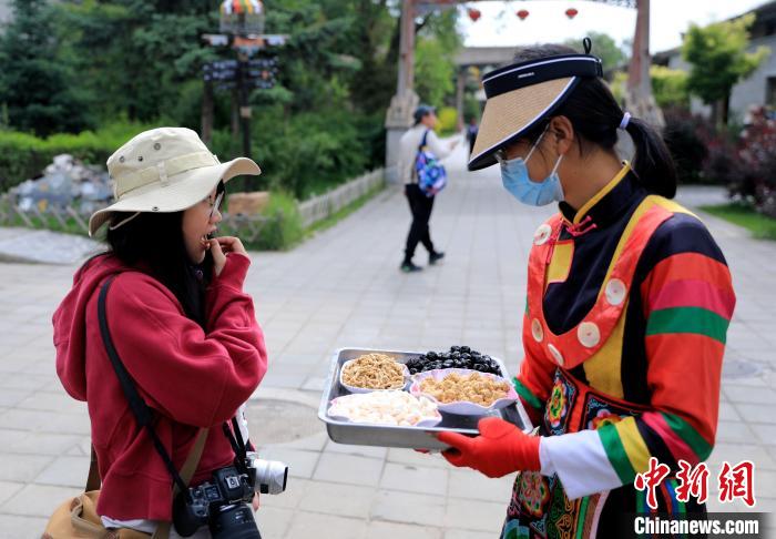 圖為身穿土族服飾的女性介紹當(dāng)?shù)靥厣〕浴！⊙Φ?攝