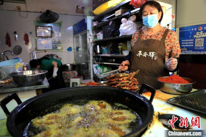圖為平安驛·河湟民俗文化體驗(yàn)地內(nèi)的商戶炸干板魚?！⊙Φ?攝