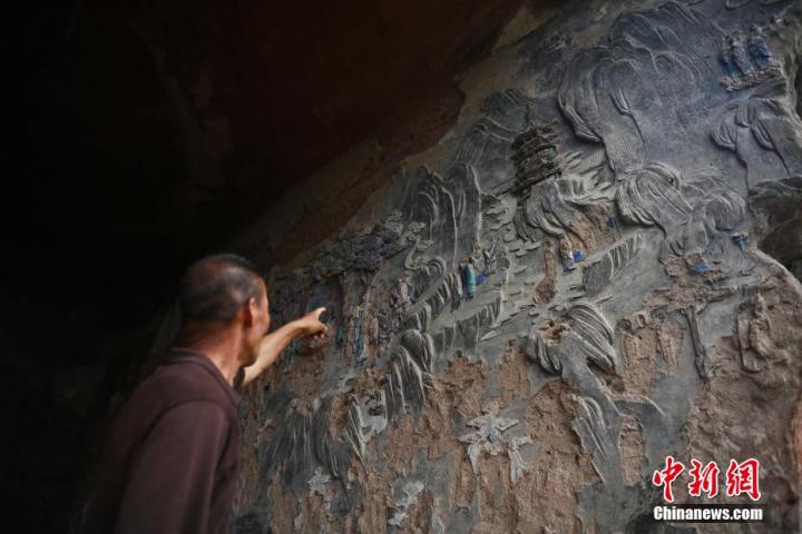 7月15日，甘肅省平?jīng)鍪袥艽h百里石窟長廊羅漢洞石窟內(nèi)，該窟文保員郭建平介紹窟內(nèi)石刻彩繪壁畫。郭建平家中三代人曾自發(fā)保護(hù)羅漢洞石窟。羅漢洞石窟遺存40余個(gè)窟龕，以北魏至清代風(fēng)格為主。中新社記者 李亞龍 攝
