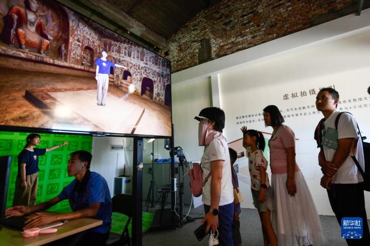 7月22日，游客體驗(yàn)“尋境敦煌——數(shù)字敦煌沉浸展”后，在虛擬演播廳拍攝一段真人與洞窟虛擬場景交互的視頻。新華社記者 郎兵兵 攝</p>
<p>