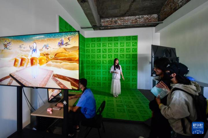7月22日，游客體驗(yàn)“尋境敦煌——數(shù)字敦煌沉浸展”后，在虛擬演播廳拍攝一段真人與洞窟虛擬場景交互的視頻。新華社記者 郎兵兵 攝</p>
<p>